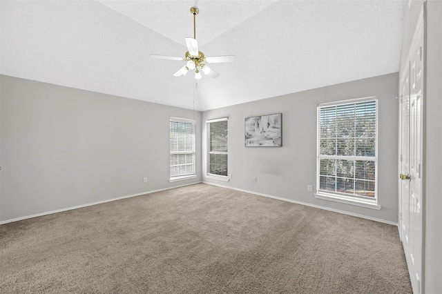 carpeted spare room with vaulted ceiling, ceiling fan, and a textured ceiling