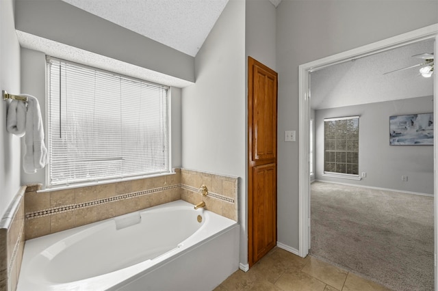 bathroom with ceiling fan, a textured ceiling, a bath, and tile patterned floors