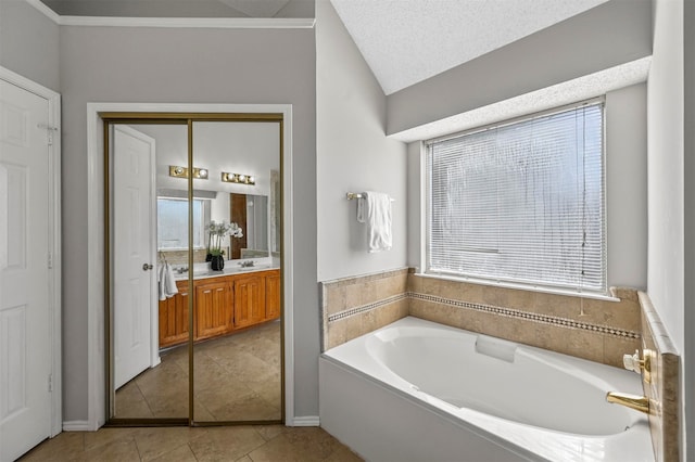 bathroom with a wealth of natural light, vaulted ceiling, a bath, and vanity