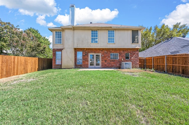 rear view of house with french doors, cooling unit, and a lawn