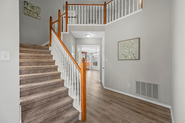 staircase featuring wood-type flooring and a high ceiling