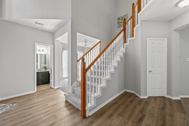 stairs with wood-type flooring, a textured ceiling, and ceiling fan