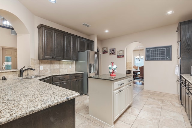 kitchen with white cabinets, dark stone countertops, sink, stainless steel fridge with ice dispenser, and backsplash