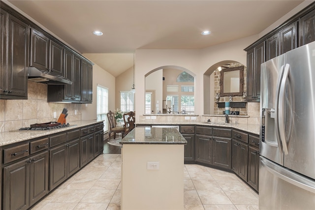 kitchen with appliances with stainless steel finishes, tasteful backsplash, dark stone counters, and a kitchen island