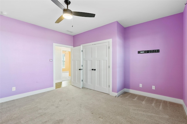 unfurnished bedroom with light colored carpet, a closet, and ceiling fan