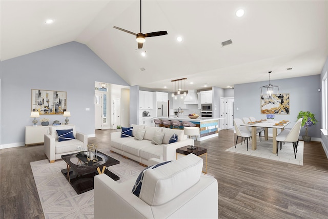 living room with ceiling fan with notable chandelier, sink, light hardwood / wood-style floors, and high vaulted ceiling