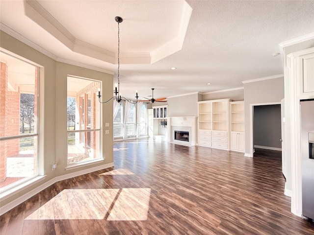 unfurnished living room with dark hardwood / wood-style floors, a raised ceiling, a textured ceiling, ornamental molding, and ceiling fan with notable chandelier