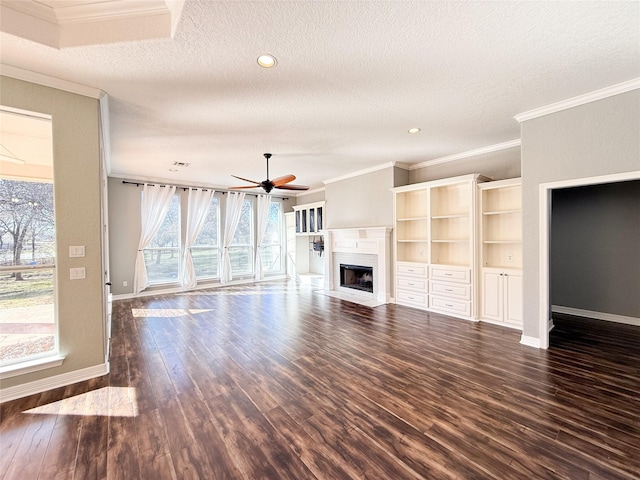 unfurnished living room featuring ceiling fan, a textured ceiling, dark hardwood / wood-style floors, and ornamental molding