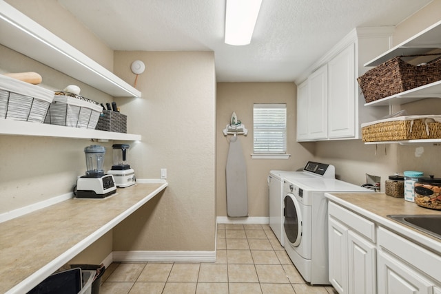 washroom featuring sink, light tile patterned flooring, separate washer and dryer, and cabinets