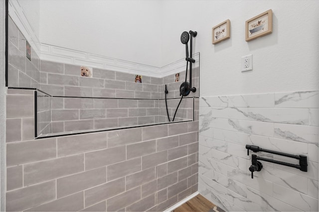 bathroom with wood-type flooring and a tile shower