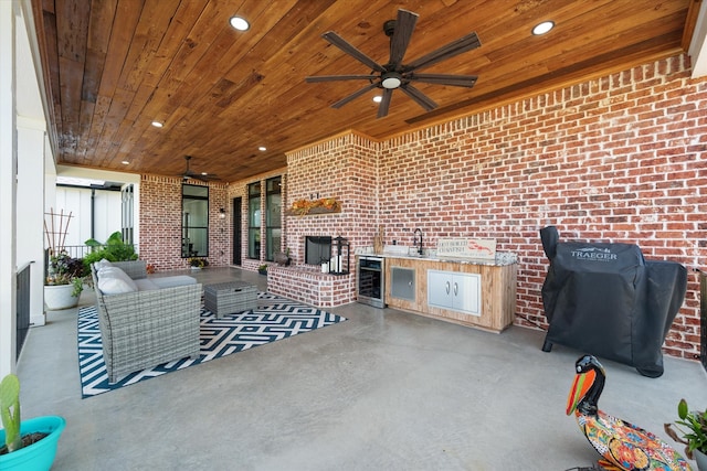 view of patio with wine cooler, ceiling fan, an outdoor kitchen, and sink