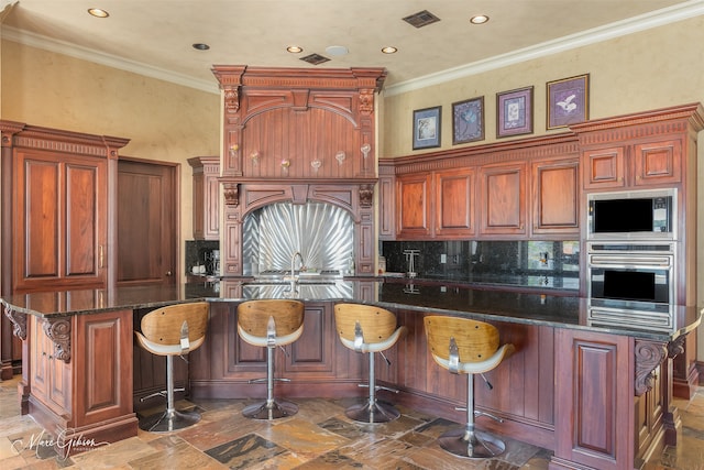 kitchen with appliances with stainless steel finishes, crown molding, and a kitchen island