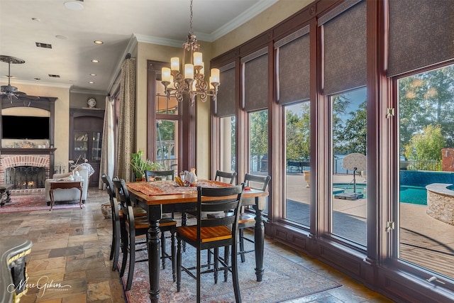 dining room with a notable chandelier, crown molding, and a brick fireplace