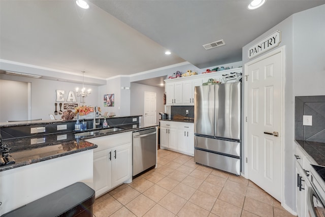 kitchen featuring appliances with stainless steel finishes, white cabinets, decorative light fixtures, ornamental molding, and sink