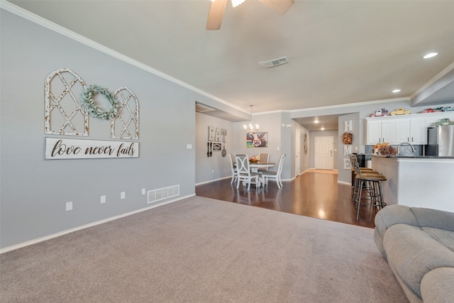 living room featuring ceiling fan with notable chandelier, dark hardwood / wood-style floors, sink, and crown molding