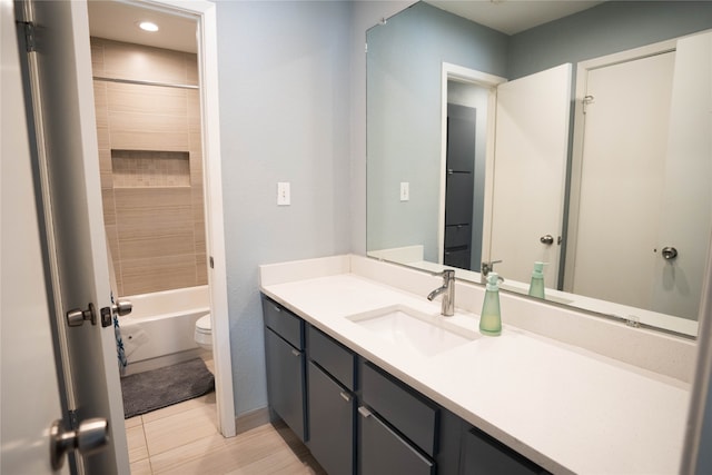 full bathroom featuring tile patterned flooring, tiled shower / bath, vanity, and toilet