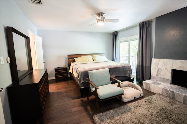 bedroom with ceiling fan, a premium fireplace, and dark wood-type flooring