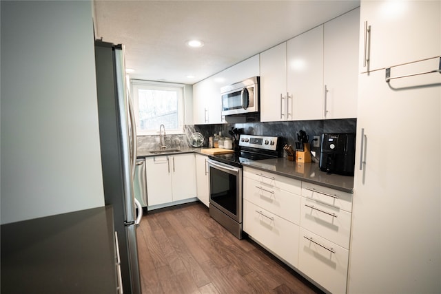 kitchen featuring decorative backsplash, white cabinets, dark hardwood / wood-style flooring, stainless steel appliances, and sink