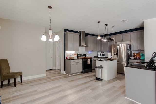 kitchen featuring gray cabinetry, hanging light fixtures, stainless steel appliances, wall chimney range hood, and a kitchen island