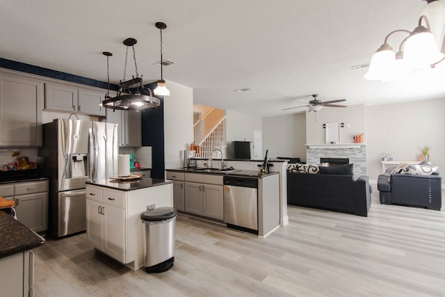 kitchen featuring appliances with stainless steel finishes, a kitchen island, gray cabinetry, and sink