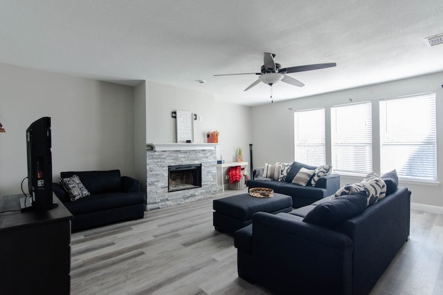 living room with a fireplace, light hardwood / wood-style floors, a wealth of natural light, and ceiling fan