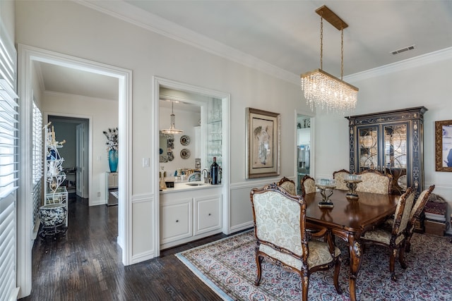 dining space with crown molding, dark hardwood / wood-style flooring, a chandelier, and sink