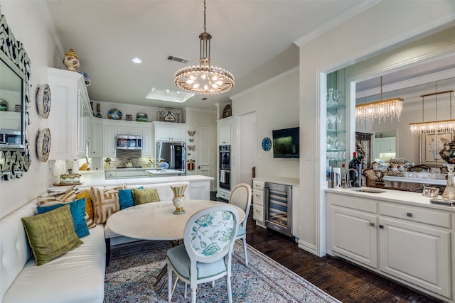 dining area with wine cooler, ornamental molding, sink, dark wood-type flooring, and a notable chandelier