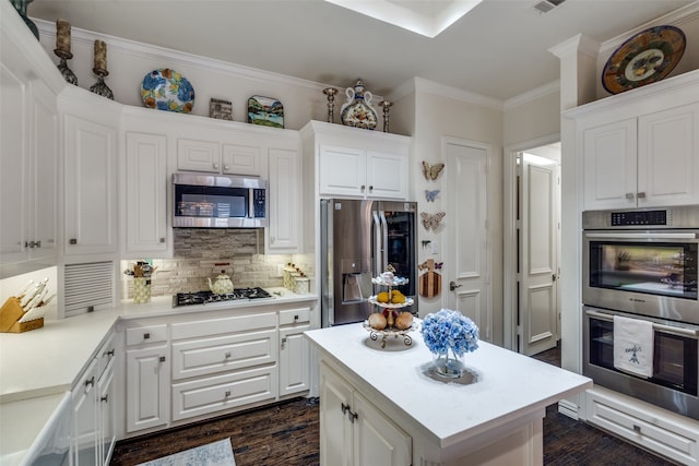 kitchen with white cabinetry, dark hardwood / wood-style flooring, stainless steel appliances, a center island, and ornamental molding