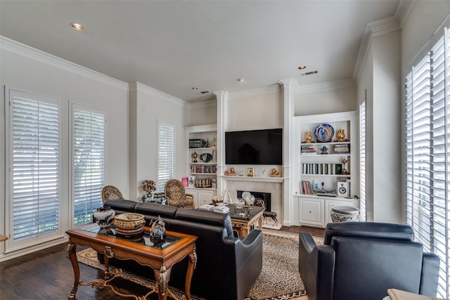 living room with built in shelves, dark hardwood / wood-style floors, ornamental molding, and a healthy amount of sunlight