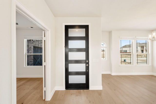 foyer entrance with an inviting chandelier and light hardwood / wood-style floors