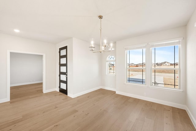 empty room with a chandelier and light wood-type flooring