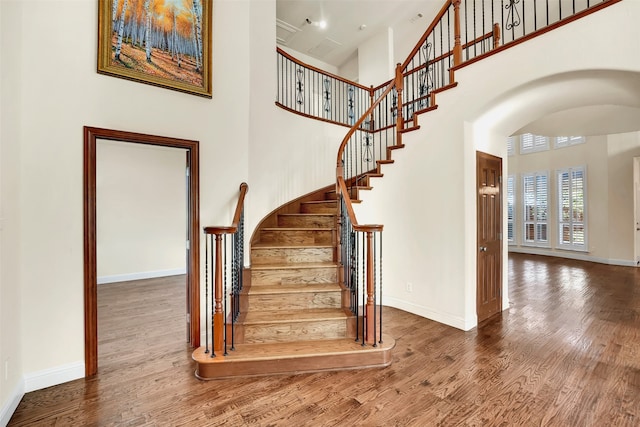 staircase with a towering ceiling and hardwood / wood-style floors