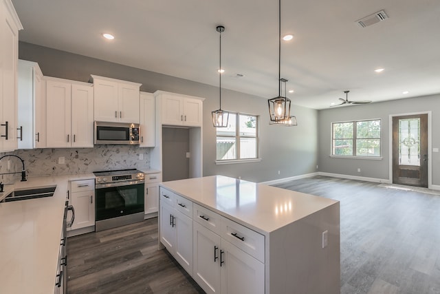 kitchen with decorative backsplash, appliances with stainless steel finishes, sink, white cabinets, and a kitchen island