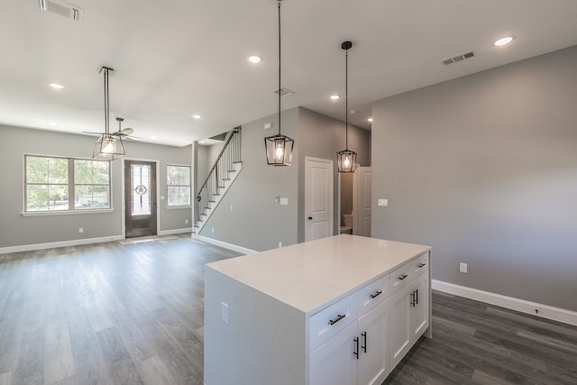 kitchen featuring a center island, white cabinetry, hanging light fixtures, and dark wood-type flooring