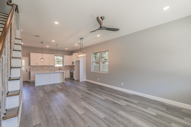 kitchen with white cabinetry, ceiling fan, decorative light fixtures, a kitchen island, and appliances with stainless steel finishes