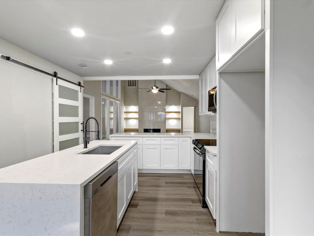 kitchen featuring sink, wood-type flooring, white cabinetry, stainless steel appliances, and a barn door