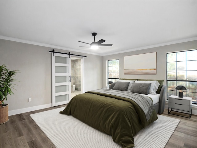 bedroom with dark wood-type flooring, a barn door, ensuite bathroom, crown molding, and ceiling fan