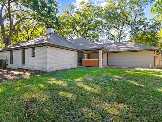 view of front of property featuring a hot tub, a front lawn, and central air condition unit