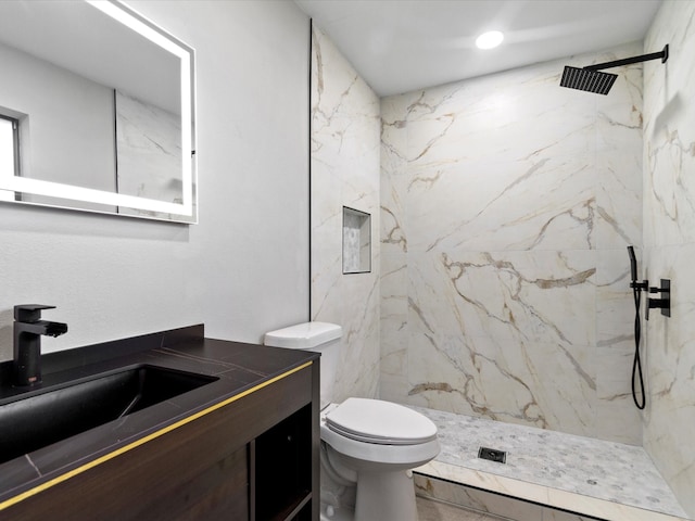 bathroom featuring a tile shower, vanity, and toilet