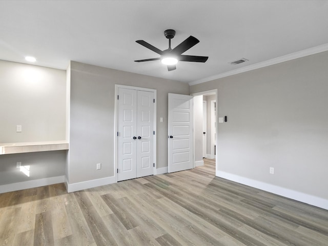 unfurnished bedroom with ornamental molding, built in desk, ceiling fan, and light hardwood / wood-style floors