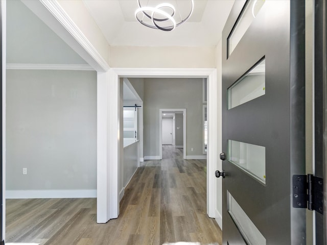 hallway with hardwood / wood-style flooring, crown molding, and a barn door