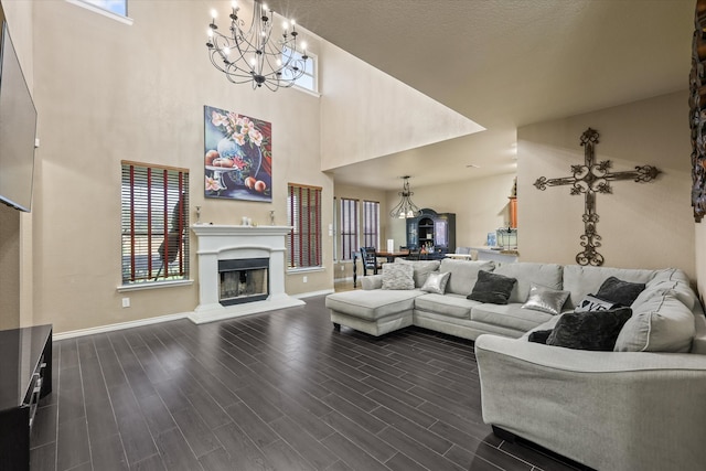 living room featuring a notable chandelier, a high ceiling, plenty of natural light, and dark wood-type flooring