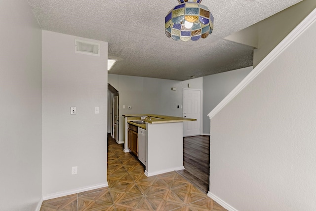 kitchen with dishwasher, a textured ceiling, and parquet floors