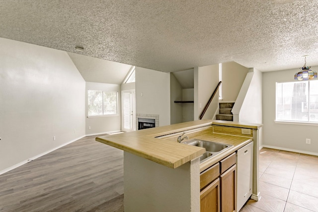 kitchen featuring dishwasher, a textured ceiling, plenty of natural light, and a kitchen island with sink