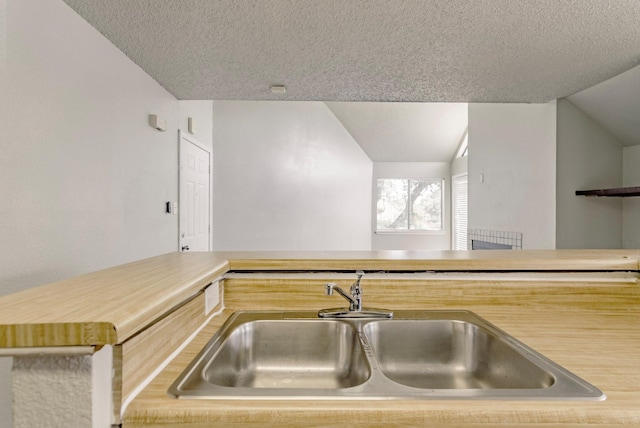 kitchen with vaulted ceiling, a textured ceiling, and sink