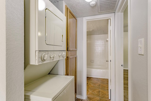 laundry room featuring stacked washer and dryer and a textured ceiling