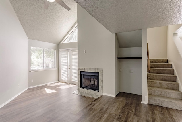 unfurnished living room featuring a textured ceiling, wood-type flooring, vaulted ceiling, and a tiled fireplace