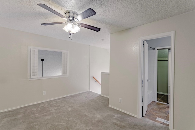 empty room featuring a textured ceiling, ceiling fan, and light colored carpet