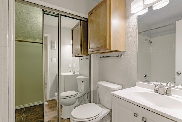 bathroom featuring a shower, vanity, toilet, and parquet flooring