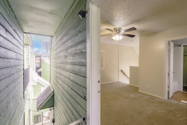 hall with light carpet and a textured ceiling